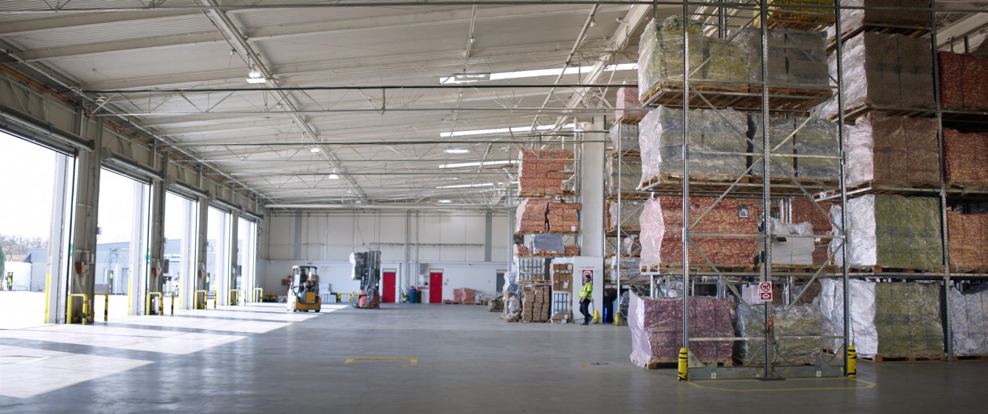 Interior of a large distribution warehouse with racking, pallets and loading docks