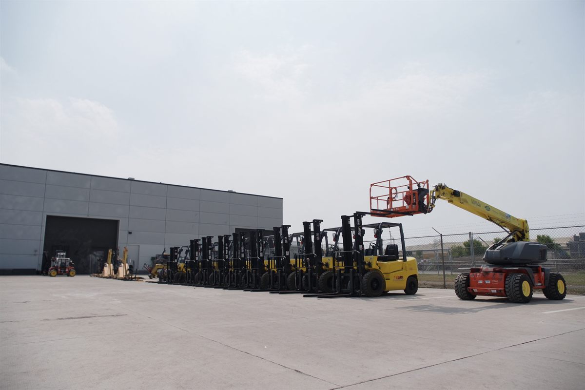 Forklifts, scissor lift and material handling equipment lined up outside a warehouse